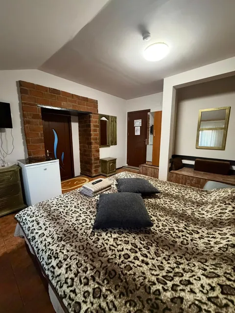 Cameră cu pat dublu, cuvertură leopard și perete de cărămidă