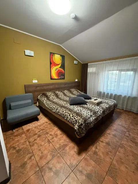 Cameră la mansardă cu perete galben și fotoliu