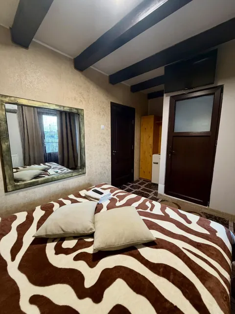 Cameră cu grinzi de lemn, oglindă mare și cuvertură zebră