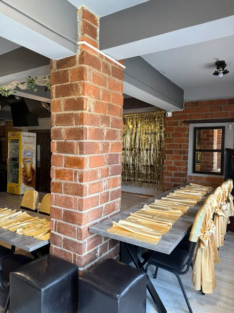Sala de club, coloană de cărămidă și mese aranjate pentru eveniment